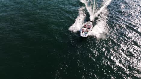 speed-boat-moving-quickly-on-a-blue-lake-summer-day-happy-people-AERIAL-TRUCKING-FOLLOW-PAN