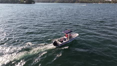 police-boat-patrolling-the-waters-of-Lake-Arrowhead-Community-California-during-sunset-AERIAL-ORBIT-FOLLOW