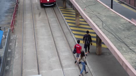 Hong-Kong-Double-Decker-Tram-in-red-livery-passing-by-tram-stop-in-Causeway-Bay,-Hong-Kong