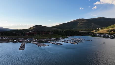 Dillon-Staudamm-Reservoir-Im-Yachthafen-Von-Silverthorne,-Colorado,-Und-Segelboote-Bei-Sonnenuntergang,-Orangefarbenes-Licht,-Das-Auf-Die-Berge-Trifft.-Lufttransportpfanne