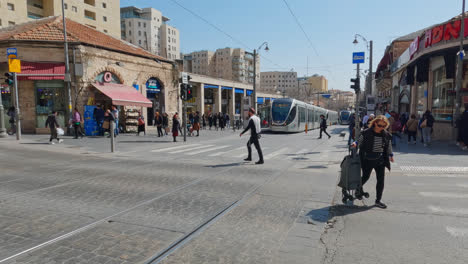 Tourists-quickly-cross-street-as-light-rail-waits-at-station-at-midday