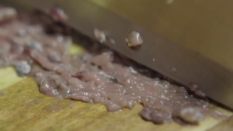 Close-up-of-chopping-anchovies-with-a-knife-on-a-cutting-board