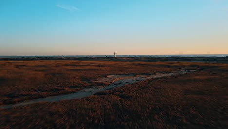 Aerial-forward-shot-of-natural-landscape-with-lighthouse-and-ocean-in-background-at-sunset-time---Provincetown,-Massachusetts