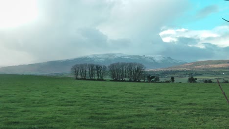 Comeragh-Mountains-Waterford-Ireland-winter-lush-green-farmland-with-snow-covered-mountains