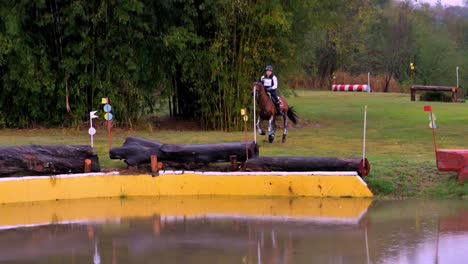Ein-Pferd-Und-Ein-Reiter-Springen-Während-Eines-Geländerennens-über-Ein-Hindernis-Ins-Wasser