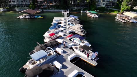 Comunidad-De-Casas-Junto-Al-Lago-Siguiendo-Un-Muelle-Y-Revelando-Grandes-Mansiones-Con-Gente-Disfrutando-Del-Día-En-El-Lago-Punta-De-Flecha-En-California-Plataforma-Aérea-Hacia-Atrás-Elevar-La-Inclinación