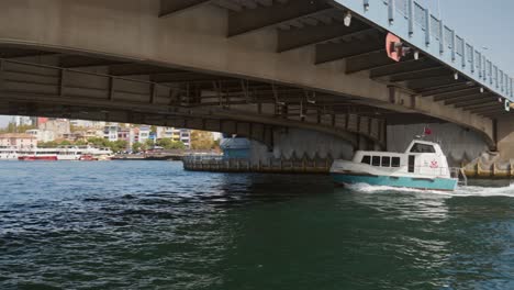 Small-boat-speeds-under-low-road-bridge-on-Golden-Horn-daytime