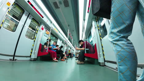 Inside-of-a-moving-metro-carriage-with-passengers-entering-at-station-stops-in-China