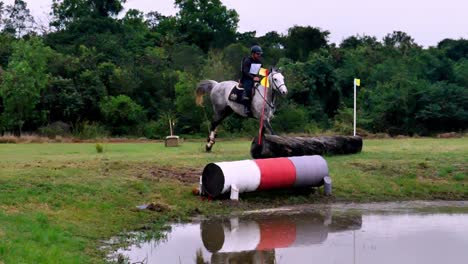 Beautiful-shot-of-a-a-gray-stallion-and-rider-jumping-over-an-obstacle