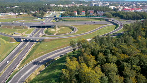 Aerial-view-of-intricate-highway-interchange,-vehicles-in-motion,-and-surrounding-greenery