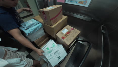 Express-Delivery-worker-pulling-in-his-dolly-with-numerous-parcels-inside-elevator
