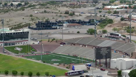 Aggie-Memorial-Stadium,-NCAA-New-Mexico-State-Aggies-football-team,-gridiron-turf-field-and-empty-stands-in-crimson-and-white-team-colors,-cinematic-aerial-shot