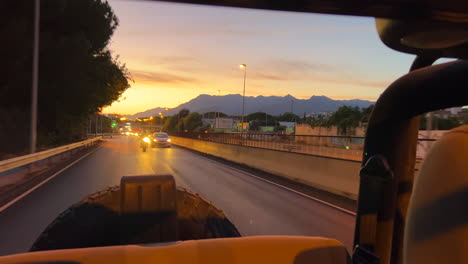 Filming-a-beautiful-orange-sunset-from-the-back-of-an-open-jeep-car,-driving-fast-on-highway,-nice-sky-in-Marbella-Spain,-4K-shot