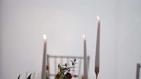 Elegant-lit-candles-with-floral-decorations-on-a-white-backdrop