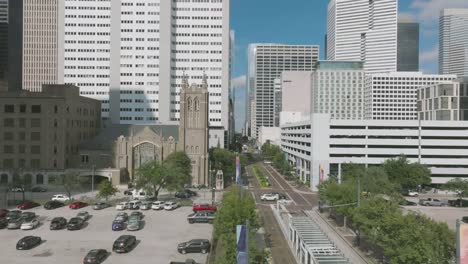 Eine-Luftaufnahme-Der-Herauszoomenden-Hauptstraße-Mit-Einem-U-Bahn-Zug,-Der-An-Einem-Sonnigen-Tag-Mit-Weißen-Wolken-In-Der-Innenstadt-Von-Houston,-Texas,-Nach-Süden-Fährt