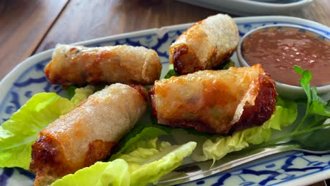 Rollitos-De-Primavera-Tradicionales-Sobre-Lechuga-Con-Salsa-De-Chile-Dulce-En-Un-Restaurante-Tailandés,-Comida-Asiática,-Toma-De-4k