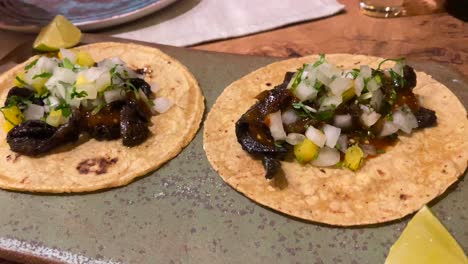 Squeezing-a-lime-on-Mexican-beef-tacos-with-onions,-traditional-juicy-authentic-beef-tacos,-4K-shot