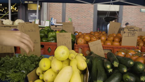 Slow-motion-dolly-shot-of-a-customer-picking-up-fresh-produce-from-a-farmers-market