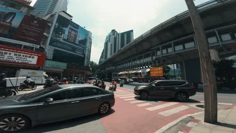 Frau-überquert-Mitten-Im-Geschäftigen-Stadtverkehr-In-Bangkok-Die-Kreuzung,-Während-Autos-Und-Motorräder-In-Bewegung-Sind