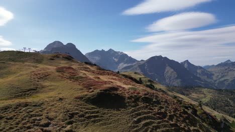 Eine-Atemberaubende-Luftaufnahme-Der-österreichischen-Alpen-Mit-Leuchtenden-Grün--Und-Brauntönen,-Einer-Atemberaubenden-Bergkulisse-Und-Einem-Klaren-Blauen-Himmel-Mit-Zarten-Wolken