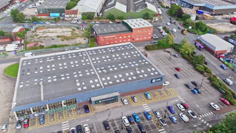 Drone-ascends-tilting-down-above-partially-full-gym-parking-lot