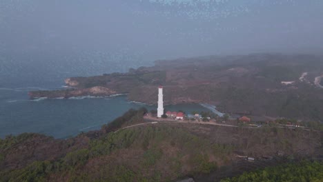 Aerial-Birds-Eye-view-orbit-shot-of-Lighthouse-at-Baron-Beach,-Indonesia-at-day