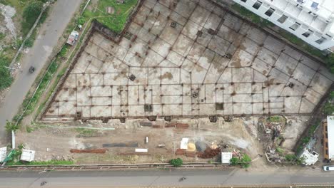 Aerial-top-side-view,-construction-work-of-high-rise-building-is-in-progress-in-which-the-basement-is-being-built-and-filled-with-concrete-and-cement