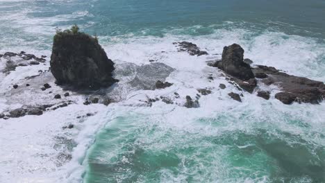 Aerial-view-of-tidal-waves-submerging-a-coral-island-with-huge-towering-rocks