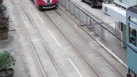 Multiple-Iconic-HK-double-decker-trams-in-colourful-livery-passing-by-tram-stop