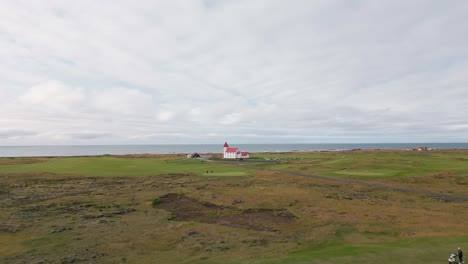 Aerial-view-of-people-carrying-golf-gear-through-the-field,-summer-days-in-south-of-Iceland