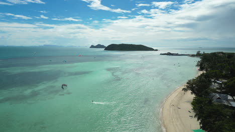 Aerial-over-the-turquoise-blue-waters-with-kite-surfers-on-Ko-Pha-Ngan-Island,-Thailand