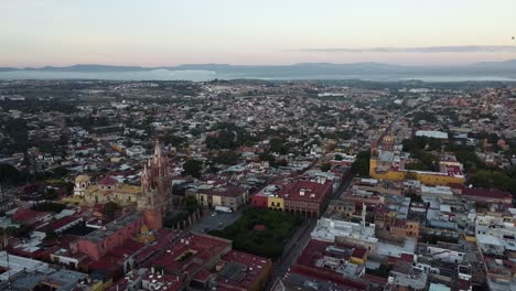 Aerial-view-over-the-colorful-city-of-San-Miguel-De-Allende,-Guanajuato-State-in-Mexico-with-view-of-the-neo-Gothic-church-Parroquia-de-San-Miguel-Arcángel-and-the-colorful-cityscape-at-golden-hour