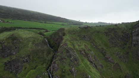Establishment-shot-of-gorgeous-cliffs-on-the-coast-overlooking-a-beautiful-rocky-green-landscape-at-Gobbins-Cliffs-in-Northern-Ireland-on-a-cloudy-day