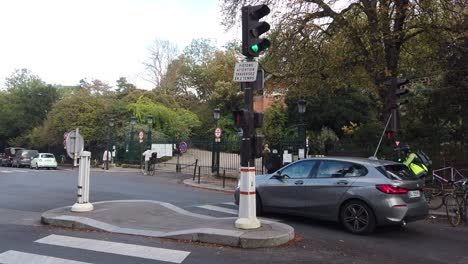 People-Cross-The-Street-in-Paris-France,-Car-Traffic-at-Park-Des-Buttes-Chaumont