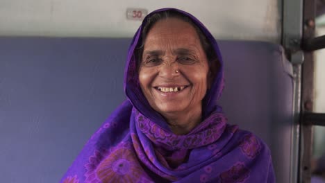 Un-Retrato-De-Una-Anciana-India-Que-Viaja-En-Un-Tren-En-La-India,-Sonríe-A-La-Cámara-Y-Está-Feliz-De-Llegar-A-Su-Destino-Natal