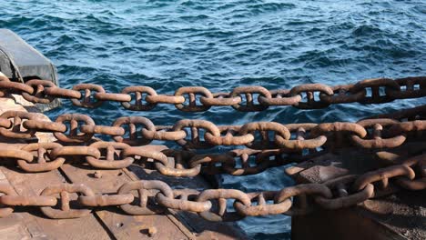 Strong-thick-rusty-metal-chains-and-blue-sea-background-in-two-time-slow-motion