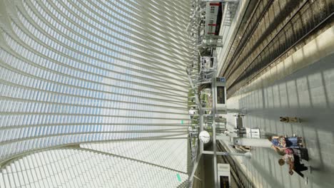 Toma-Vertical-En-Primera-Persona-De-Un-Pasajero-Bajando-De-Una-Escalera-Mecánica-Dentro-De-La-Estación-De-Tren-De-Lieja-Guillemins-En-Lieja,-Bélgica