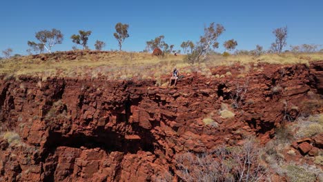 Isolierter-Mann-Sitzt-Am-Felsigen-Rand-Des-Berges-Und-Bewundert-Das-Panorama-In-Der-Wüste-Westaustraliens