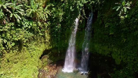Two-streams-of-waterfall-falling-down-in-middle-of-the-rainforest-with-thick-natural-vegetation