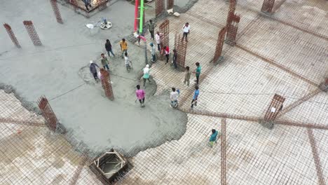 aerial-camera-passing-up,-construction-of-high-rise-building-is-in-progress-in-which-basement-is-being-building-and-filling-with-concrete-and-cement