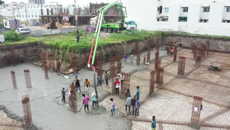 Aerial-view,-construction-work-of-high-rise-building-is-going-on-in-which-basement-is-being-built-and-concrete-and-cement-filling