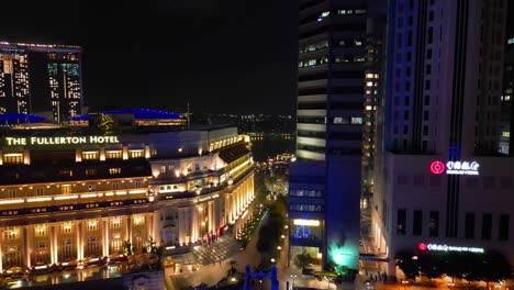 Aerial-Tilt-of-The-Fullerton-Hotel-and-Bank-of-China-in-Singapore-at-Night