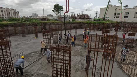 Aerial-view,-construction-work-of-high-rise-building-is-going-on-in-which-basement-is-being-built-and-concrete-and-cement-filling