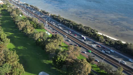 Aerial-top-down-shot-showing-busy-traffic-on-coastal-state-route-2-in-Perth-City-at-sunset---tilt-up-view