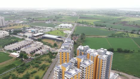 Aerial-drone-camera-moving-from-city-to-village-with-green-fields-on-both-sides-of-the-road