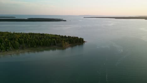 Aerial-descent-of-Marquette-Island-peninsula-golden-hour-flat-water,-Lake-Huron,-Les-Cheneaux-Islands,-Hessel