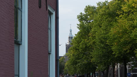 Rote-Backsteinfassade-Der-Kirche-Mit-üppigen-Grünen-Bäumen-In-Der-Ferne-In-Gouda,-Niederlande