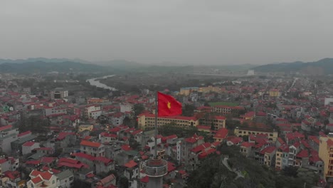 Flying-backwards-over-big-Vietnam-flag-at-lang-son-city,-aerial