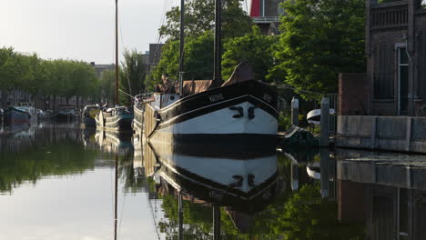 Vintage-Boat-Moored-On-Canal-Turfsingel-With-Mirrored-Reflection-in-Gouda,-Netherlands
