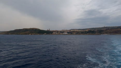 Vista-Desde-Un-Barco-Sobre-El-Agua-Y-La-Costa-De-La-Valeta,-Malta.
